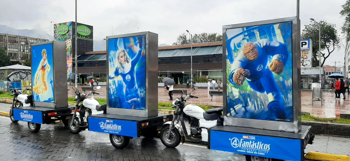 Motos valla publicitarias con avisos de la pelicula de los 4 fantásticos frente al carulla de la 85