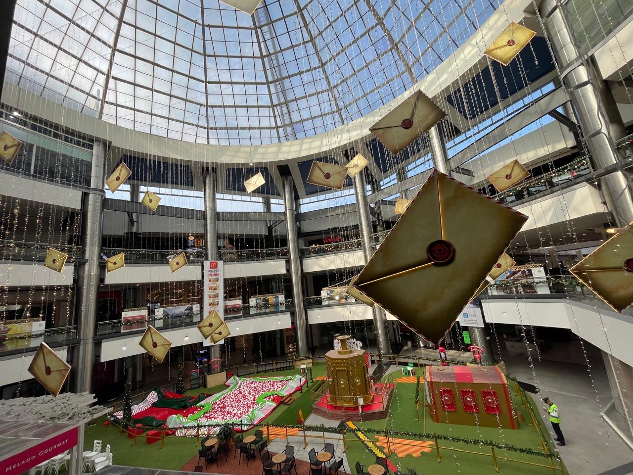 Decoración navideña aérea en centro comercial con sobres rojos gigantes y luces colgantes