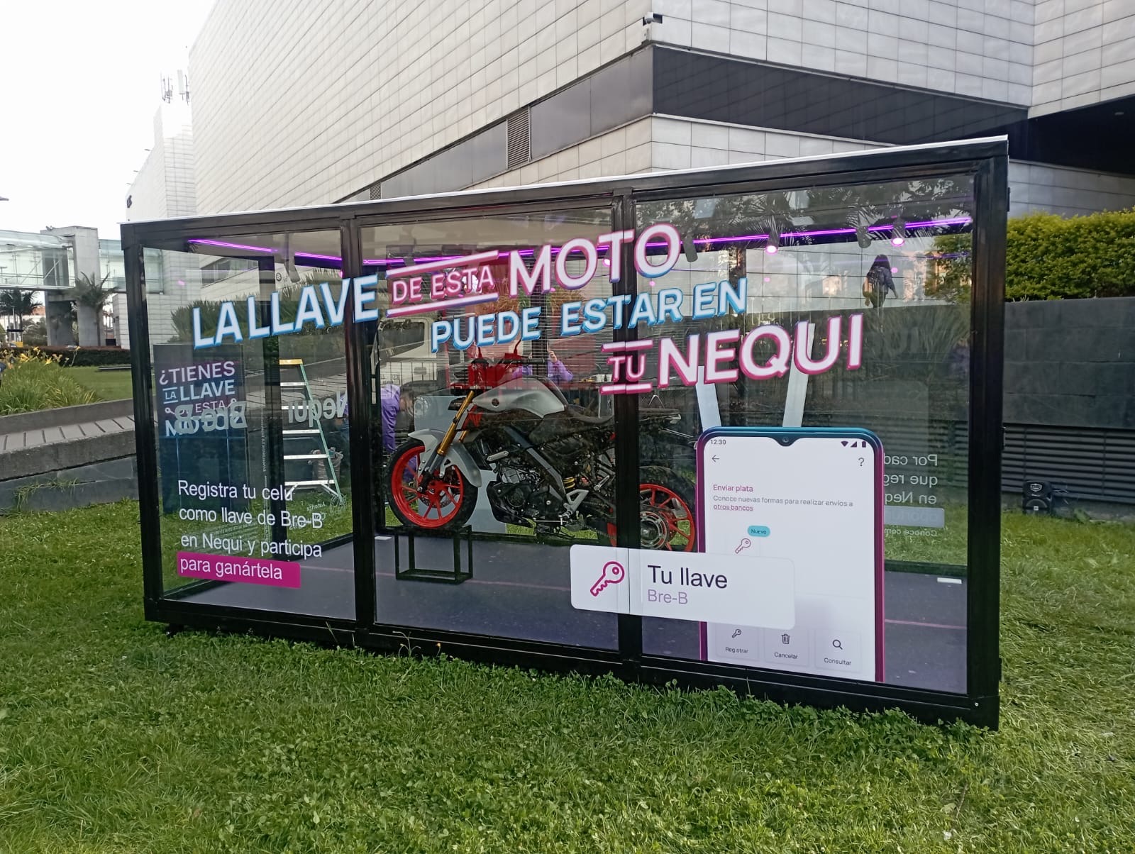 Estructura tipo container de vidrio con branding de Nequi ubicada en plaza pública